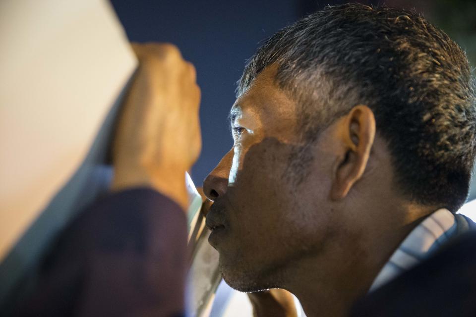 An anti-government protester of People's Democratic Reform Committee (PDRC) peeks over a barricade after hearing three gunshots in the distance near the MBK Center in the Pathumwan district, Wednesday, Jan. 15, 2014, in Bangkok, Thailand. Gunshots rang out in the heart of Thailand's capital overnight in an apparent attack on anti-government protesters early Wednesday that wounded at least two people and ratcheted up tensions in Thailand's deepening political crisis. (AP Photo/John Minchillo)