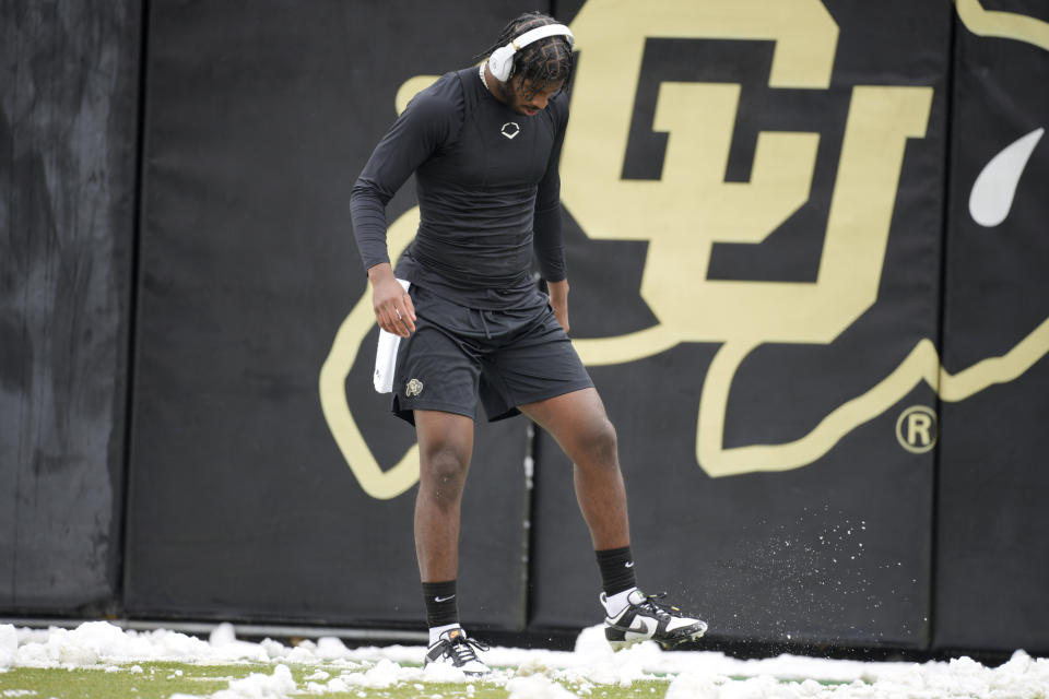 Colorado quarterback Shedeur Sanders clears snow from the field as he warms up before the team's spring NCAA college football game Saturday, April 22, 2023, in Boulder, Colo. (AP Photo/David Zalubowski)