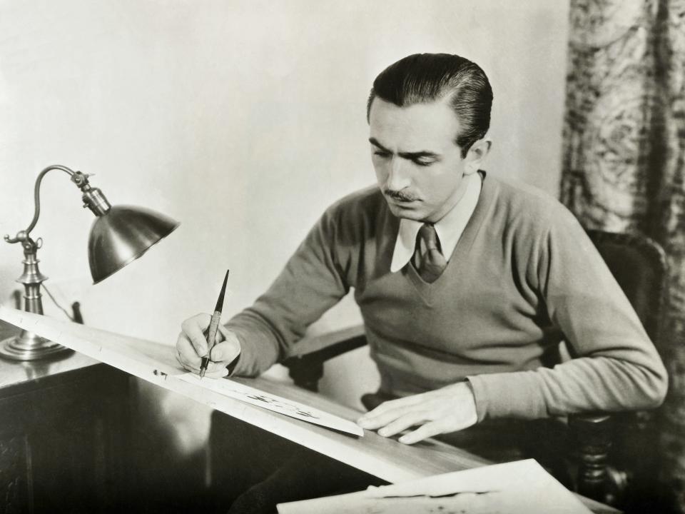 Walt drawing at a slanted desk.