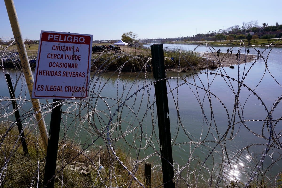 Migrants cross the Rio Grande into the U.S. from Mexico behind Concertina wire and a sign warning that it's dangerous and illegal to cross, Wednesday, Jan. 3, 2024, in Eagle Pass, Texas (Copyright 2024 The Associated Press. All rights reserved)
