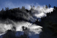 Man-made snow is blown from snowmaking equipment near the summit of Pleasant Mountain ski resort, Thursday, Dec. 21, 2023, in Bridgton, Maine. The New England ski industry is working to recover from a disastrous rain storm that washed away much of the snow just before the Christmas vacation season. (AP Photo/Robert F. Bukaty)