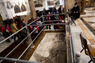 In this Thursday, Dec. 6, 2018 photo, visitors walk by a renovated part of a mosaic inside the Church of the Nativity, built atop the site where Christians believe Jesus Christ was born, in the West Bank City of Bethlehem. City officials are optimistic that the renovated church will help add to a recent tourism boom and give a boost to the shrinking local Christian population. (AP Photo/Majdi Mohammed)