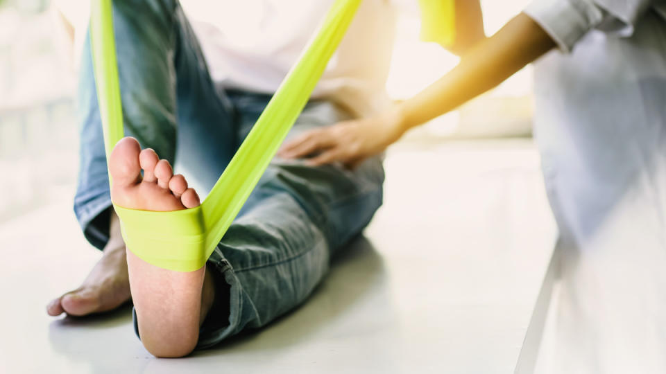 A woman stretching her foot with a green band to help cure plantar fasciitis in one week