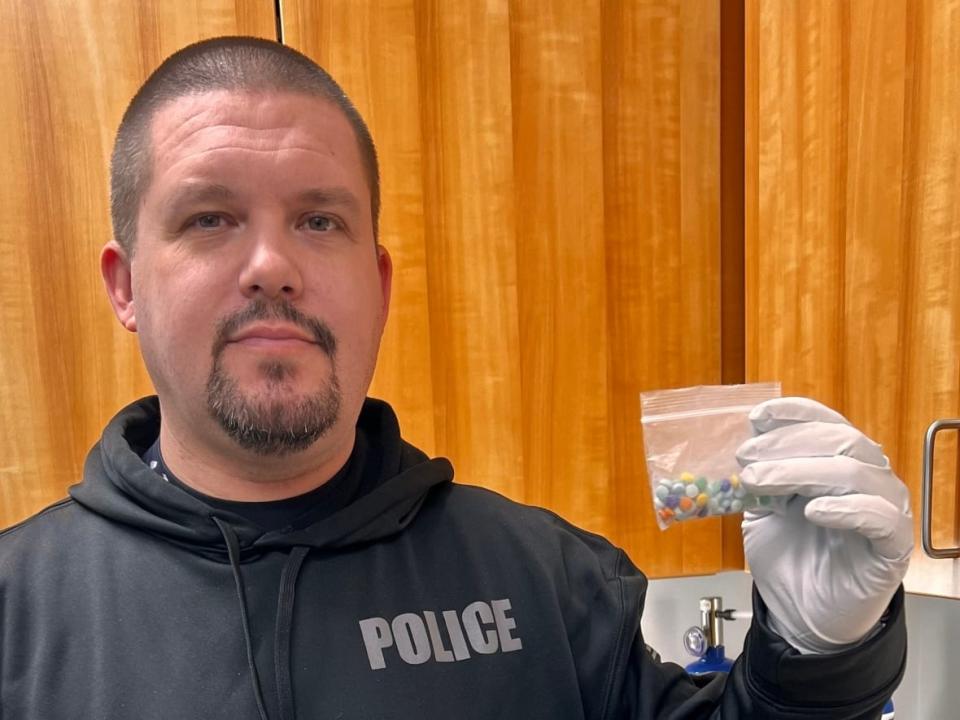 Officer James Michels with the Skagway Police Department in Skagway, Alaska, holds some suspected fentanyl pills seized by police in the community on Sunday. The seizure was made after 2 local residents died of suspected overdoses. (Skagway Police Department - image credit)