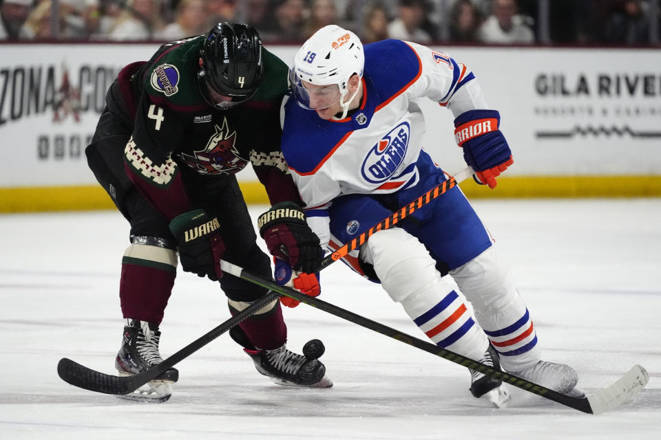 Edmonton Oilers center Adam Henrique (19) and Arizona Coyotes defenseman Juuso Valimaki (4) vie for the puck during the second period of an NHL hockey game Wednesday, April 17, 2024, in Tempe, Ariz. (AP Photo/Ross D. Franklin)