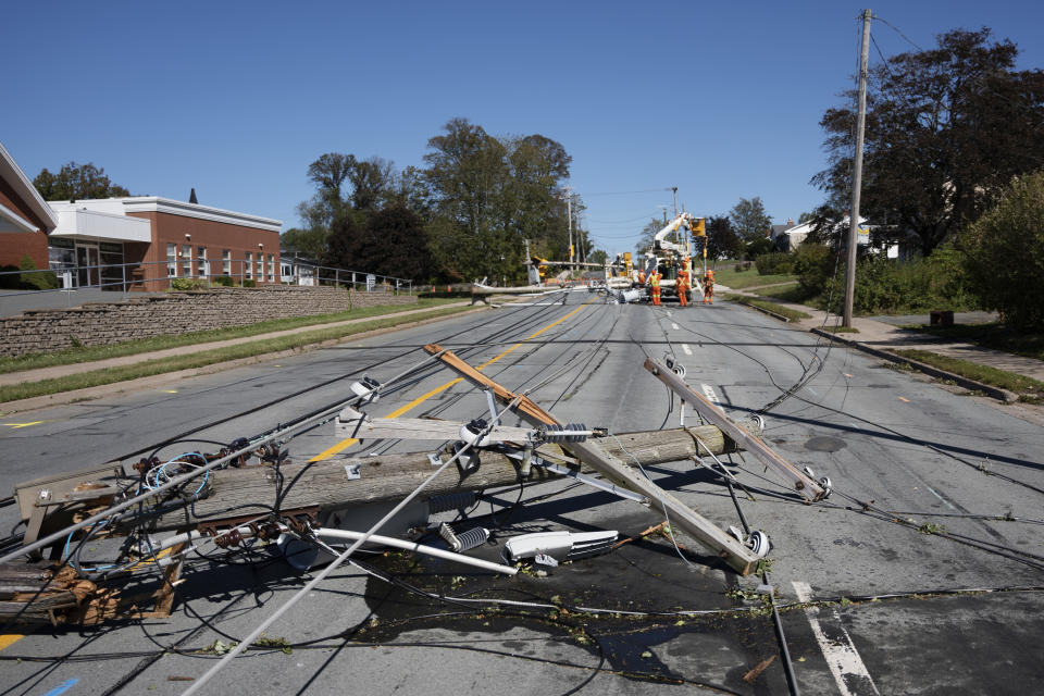 A downed power pole lays across a road as workers assess the damage caused by post-tropical storm Fiona in Dartmouth, Nova, on Sunday, Sept. 25, 2022. Hundreds of thousands of people in Atlantic Canada remain without power and officials are trying to assess the scope of devastation from former Hurricane Fiona. It swept away houses, stripped off roofs and blocked roads across the country’s Atlantic provinces. (Darren Calabrese/The Canadian Press via AP)