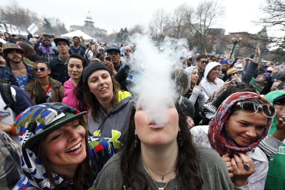 Con el capitolio estatal de Colorado como trasfondo, fiesteros bailan y fuman marihuana durante el festival 4/20 de la droga en Denver, Colorado, el sábado, 19 de abril del 2014. (Foto AP/Brennan Linsley)