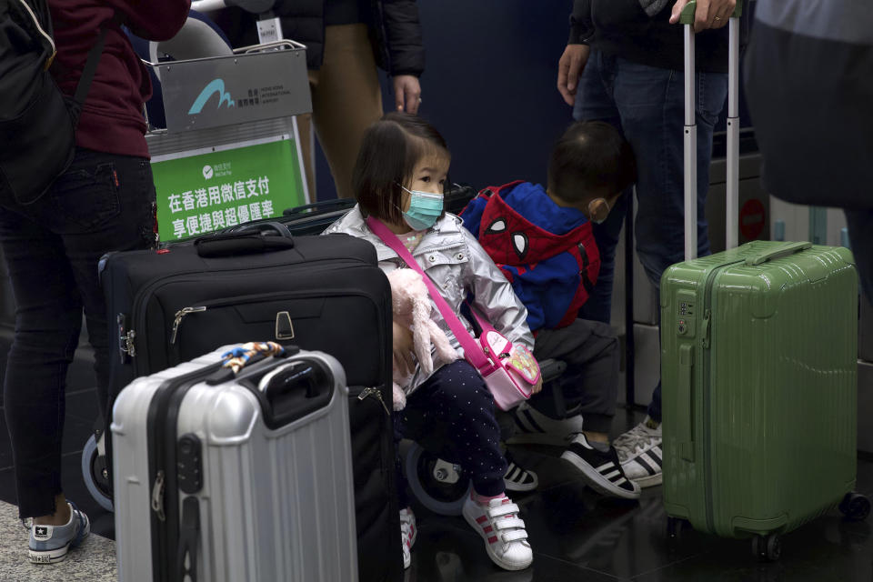 A girl wearing a face mask sits among suitcases at Hong Kong International Airport in Hong Kong, Tuesday, Jan. 21, 2020. Face masks sold out and temperature checks at airports and train stations became the new norm as China strove Tuesday to control the outbreak of a new coronavirus that has reached four other countries and territories and threatens to spread further during the Lunar New Year travel rush. (AP Photo/Ng Han Guan)
