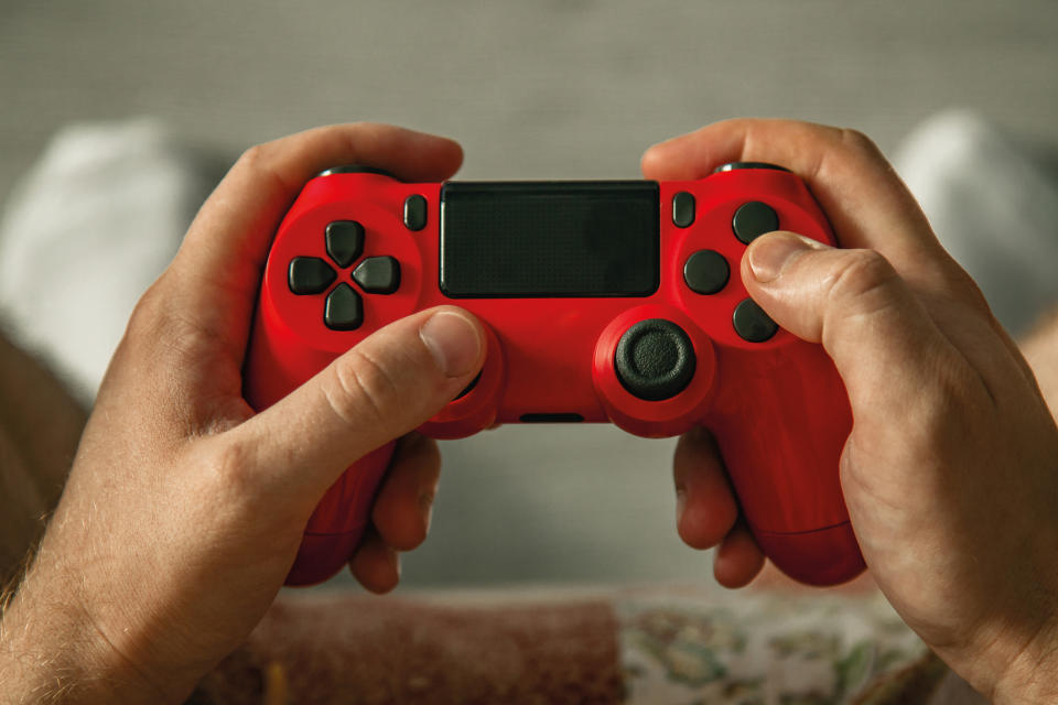 Two hands holding a red game controller, viewed from the player's perspective