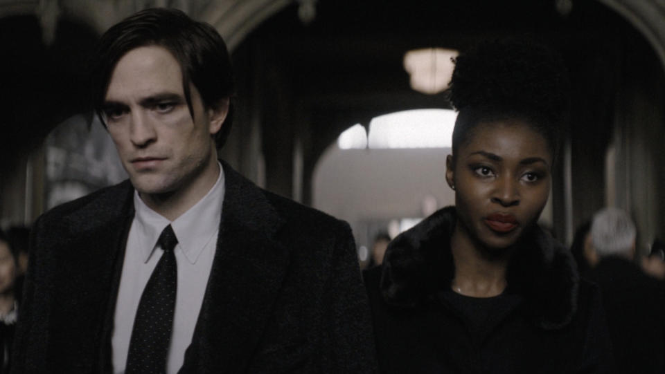 A still from The Batman shows Robert Pattinson as Bruce Wayne and Jayme Lawson as Bella Real inside a church