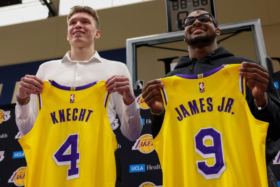 Lakers draft picks Dalton Knecht, left, and Bronny James hold up their jerseys.