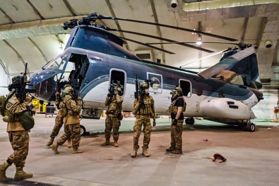 Fighters inside a hangar next to a military helicopter