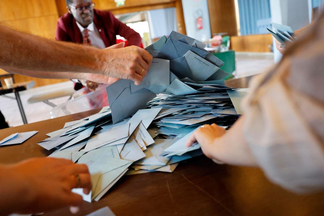 Polling station workers begin counting ballots during the second round of the legislative elections, Sunday, July 7, 2024 in Schiltgheim, eastern France. Voting is underway in mainland France on Sunday in pivotal runoff elections that could hand a historic victory to Marine Le Pen's far-right National Rally and its inward-looking, anti-immigrant vision, or produce a hung parliament and political deadlock. (AP Photo/Jean-Francois Badias)