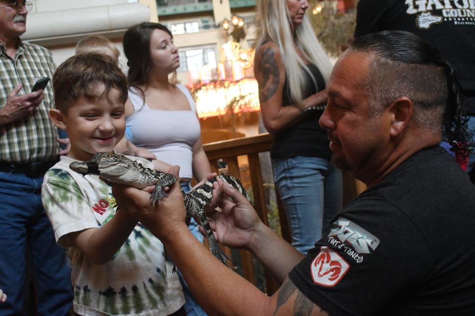 Leo Parfait (right) of Louisiana Gator Country in Natchitoches helps Kayden Ponthier, 6, of Bunkie hold a small alligator at the Gator Feeding Show at the Paragon Casino Resort in Marksville.