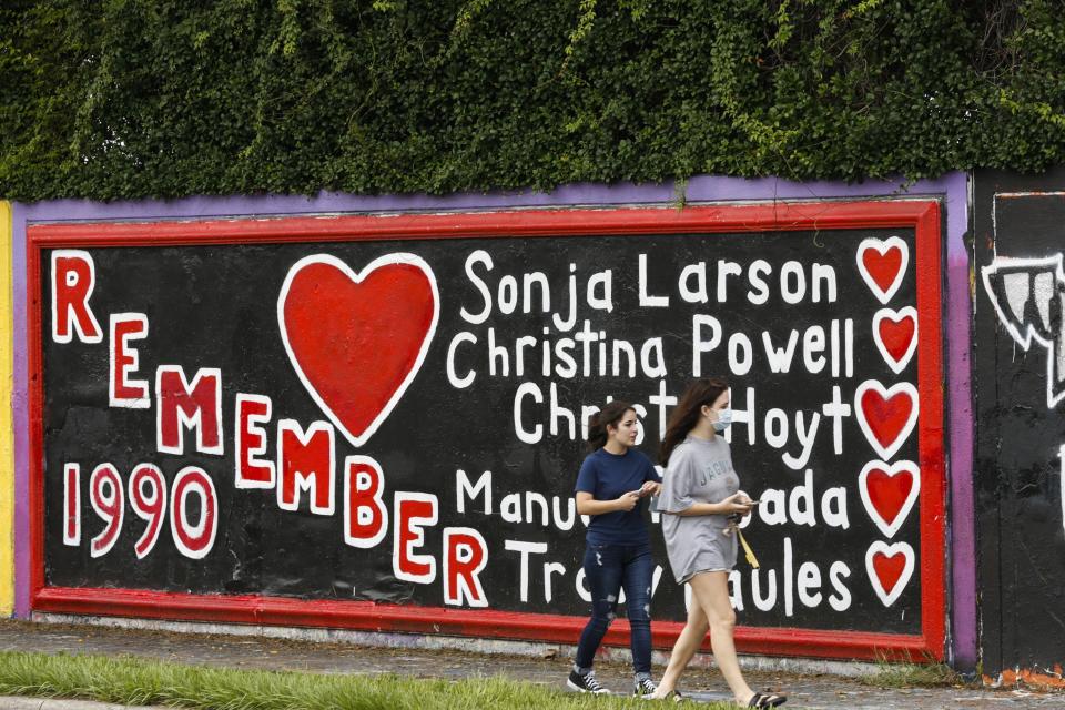 People pass by the mural on SW 34th Street on Aug. 22, 2020, in Gainesville, Fla., honoring the five students who were murdered by Danny Rolling in August of 1990. This year, 2020, is the 30th anniversary of the grizzly events that happened Gainesville. (Sam Thomas/The Gainesville Sun via AP)