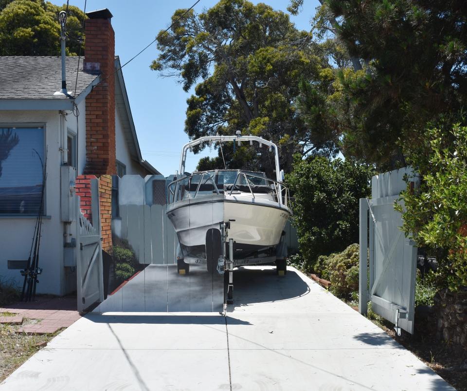 The opposite half of Etienne Constable's boat is visible from behind a hyper-realistic mural, painted by next-door neighbor Hanif Panni. The two men decided to make the mural to comply with a city rule in a creative way.