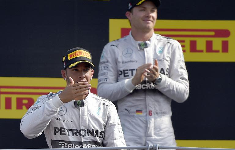 Second placed Mercedes' driver Nico Rosberg (back) applauds as winner, teammate Lewis Hamilton, arrives on the podium after the Italian Formula One Grand Prix race, at the Autodromo Nazionale circuit in Monza, on September 7, 2014