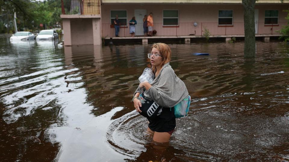 PHOTO: Makatla Ritchter wades through flood waters after having to evacuate her home when the flood waters from Hurricane Idalia inundated it, Aug. 30, 2023, in Tarpon Springs, Florida.  (Joe Raedle/Getty Images)