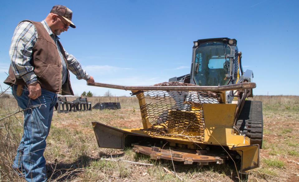 Jimmy Emmons explains the workings of a mulching attachment he uses to take down old stands of burned redcedar at his ranch near Leedey.