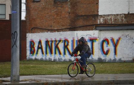 A man rides his bike past graffiti that reads "Bankruptcy" in Detroit, Michigan, December 3, 2013. REUTERS/Joshua Lott