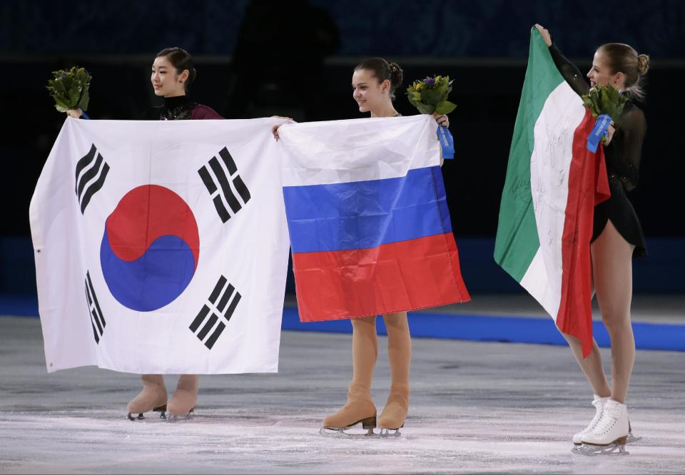 Adelina Sotnikova of Russia, centre, Yuna Kim of South Korea, left, and Carolina Kostner of Italy celebrate with their national flags as they pose for photographers following the flower ceremony for the women's free skate figure skating final at the Iceberg Skating Palace during the 2014 Winter Olympics, Thursday, Feb. 20, 2014, in Sochi, Russia. Sotnikova placed first, followed by Kim and Kostner. (AP Photo/Bernat Armangue)