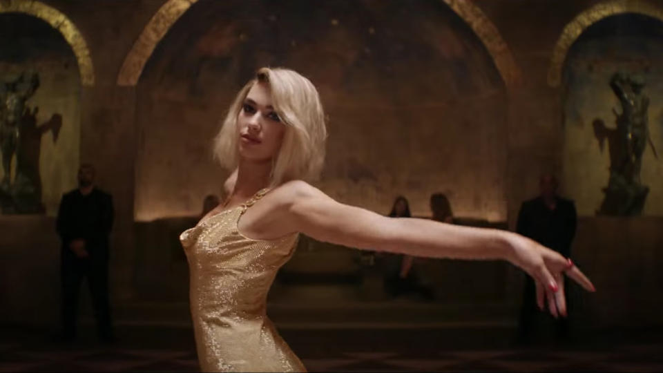 Dua Lipa dancing in a gold dress in Argylle.