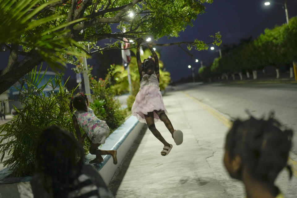 A Haitian child swings from a tree branch at the Five batey in the Bahoruco province, Dominican Republic, Wednesday, May 15, 2024. The Dominican Republic bateyes are settlements of mostly Haitian immigrants and descendents working in the nearby sugarcane plantations. (AP Photo/Matias Delacroix)