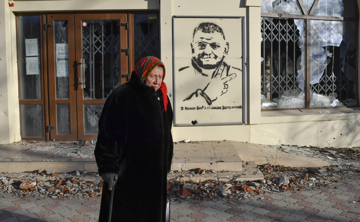 CAPTION CORRECTS TRANSLATION An elderly woman walks along a street against background of a graffiti depicting General Valery Zaluzhny, head of Ukraine's armed forces and writing ""God is with us and commander Zaluzhny" in the area of the heaviest battles with the Russian invaders in Bakhmut, Ukraine, Tuesday, Dec. 20, 2022. (AP Photo/Andriy Andriyenko)