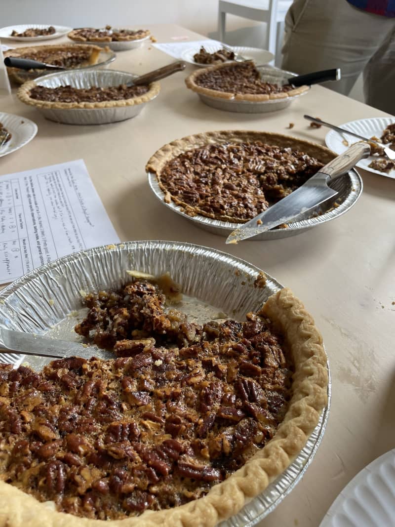 pecan pies on table in silver tins with pieces taken out and crubs on table