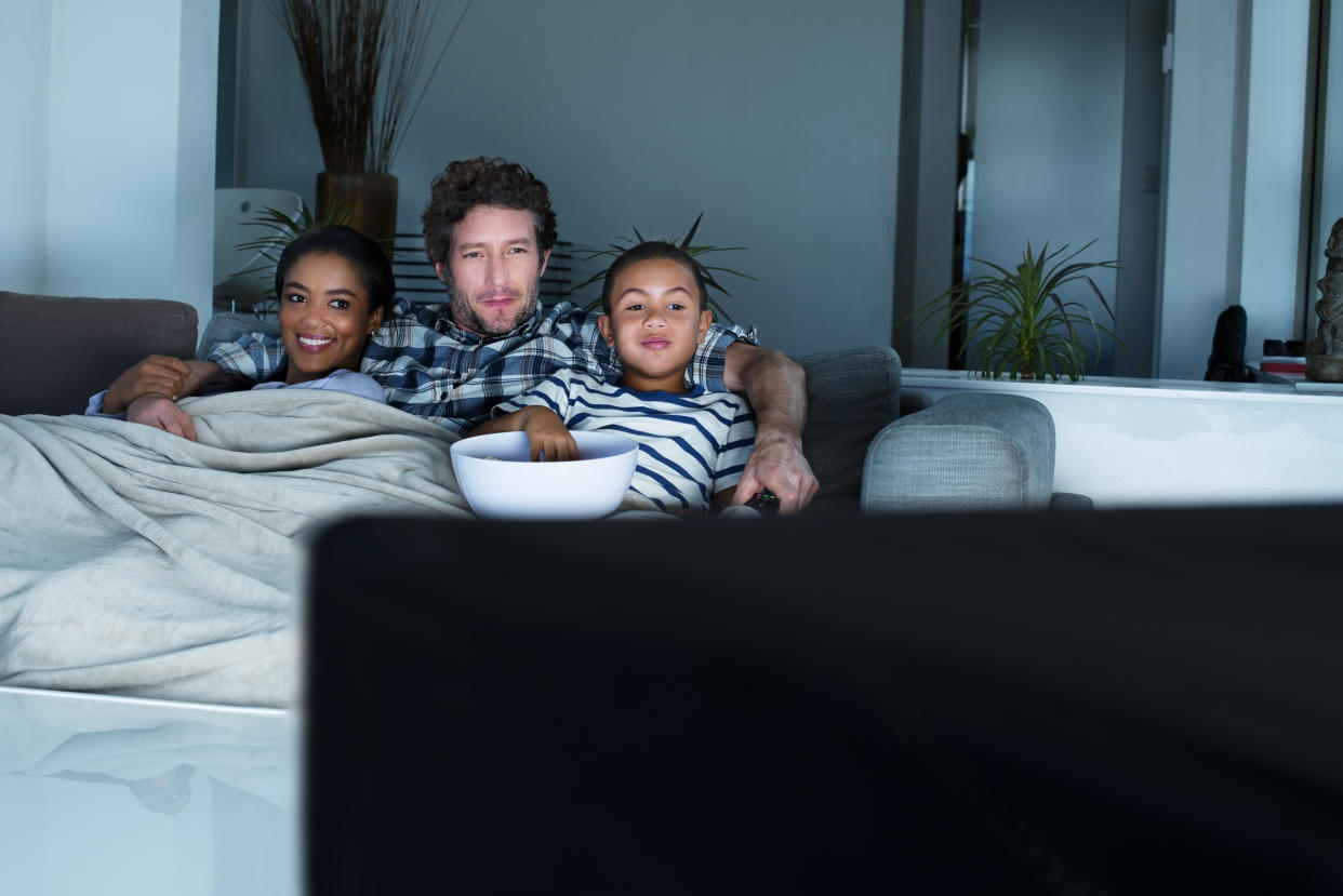 Multi-ethnic family having popcorn while watching TV in living room at home