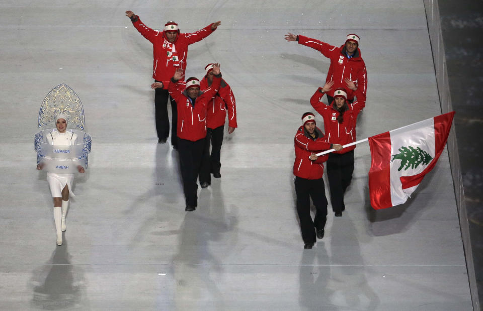 Alexandre Mohbat of Lebanon wave his national flag and enters the arena with teammates during the opening ceremony of the 2014 Winter Olympics in Sochi, Russia, Friday, Feb. 7, 2014. (AP Photo/Charlie Riedel)