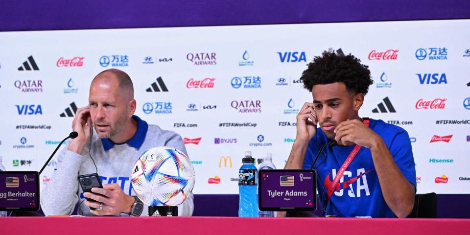 Gregg Berhalter and Tyler Adams listen at a World Cup press conference.