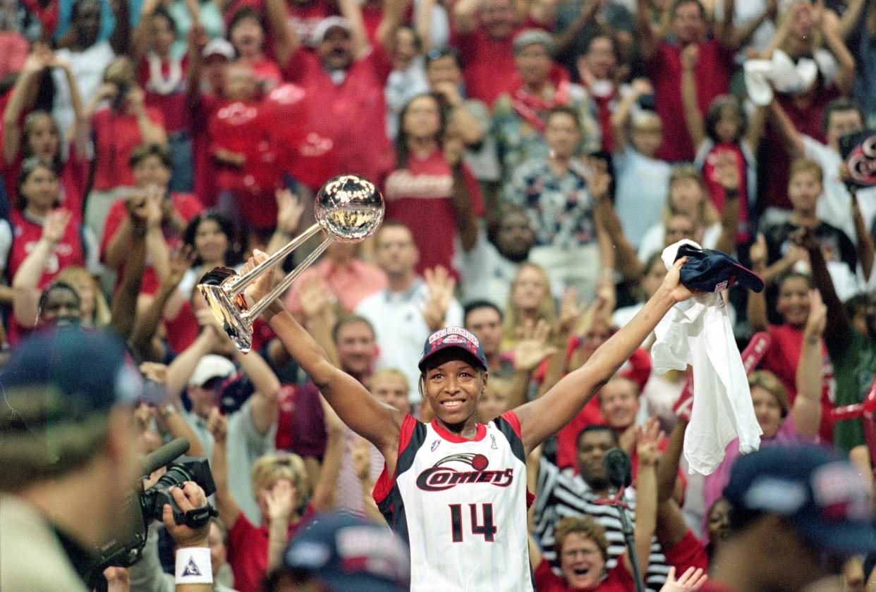 Cynthia Cooper raises her arms with the championship trophy in one hand as she celebrates the Comets' fourth straight title.