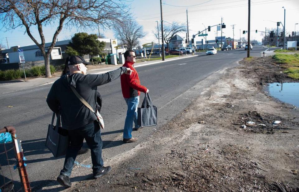 Volunteers Matt Orante, left, and Jeremy Howell walk along Kansas Avenue looking for homeless residents during Stanislaus County’s point in time count of the homeless population in Modesto, Calif., Thursday, Jan. 26, 2023.