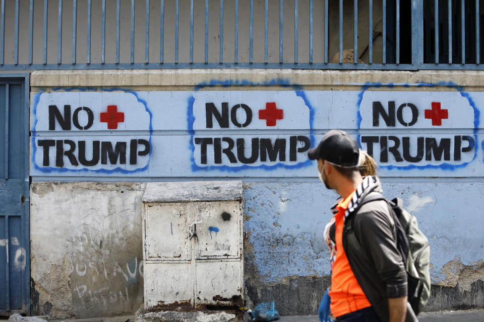 CARACAS, VENEZUELA - MARCH 26: A couple walks past graffitis against  US President Donald Trump on March 26, 2020 in Caracas, Venezuela. Attorney General William Barr announced the charges against Maduro on drug crimes and offered a 15 million dollar reward for information leading to the capture of the Venezuelan ruler. (Photo by Leonardo Fernandez Viloria/Getty Images)