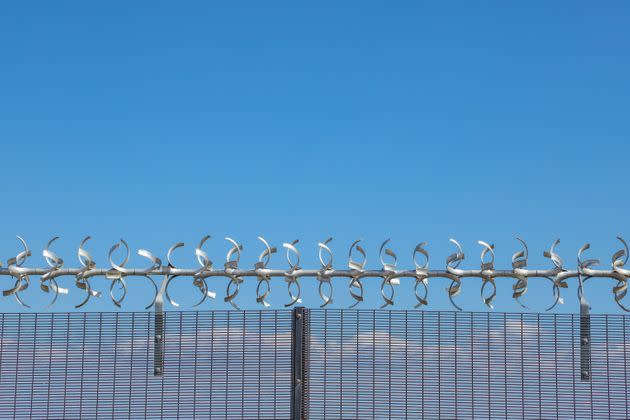 Restricted area.  Close up of a silver colored razor wire security fence against a blue sky