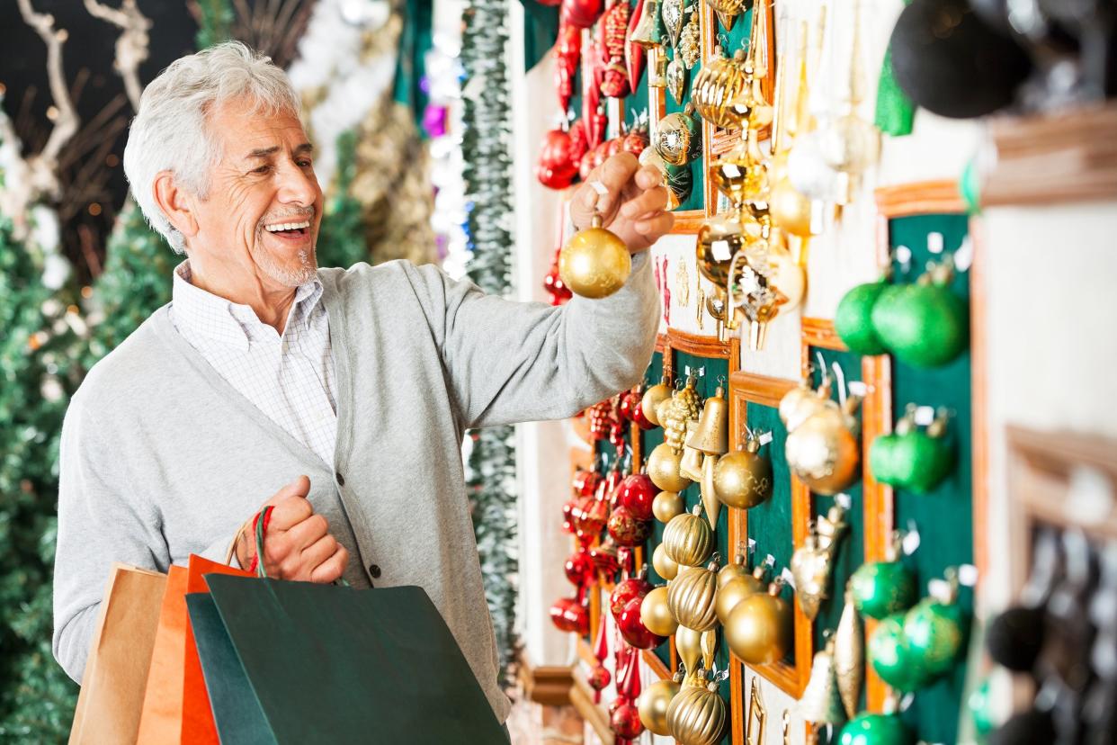 happy senior man choosing Christmas balls at store