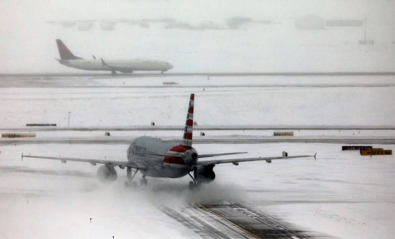 An American Airlines jet taxis down a snow-covered runway after a snowstorm at Denver International Airport