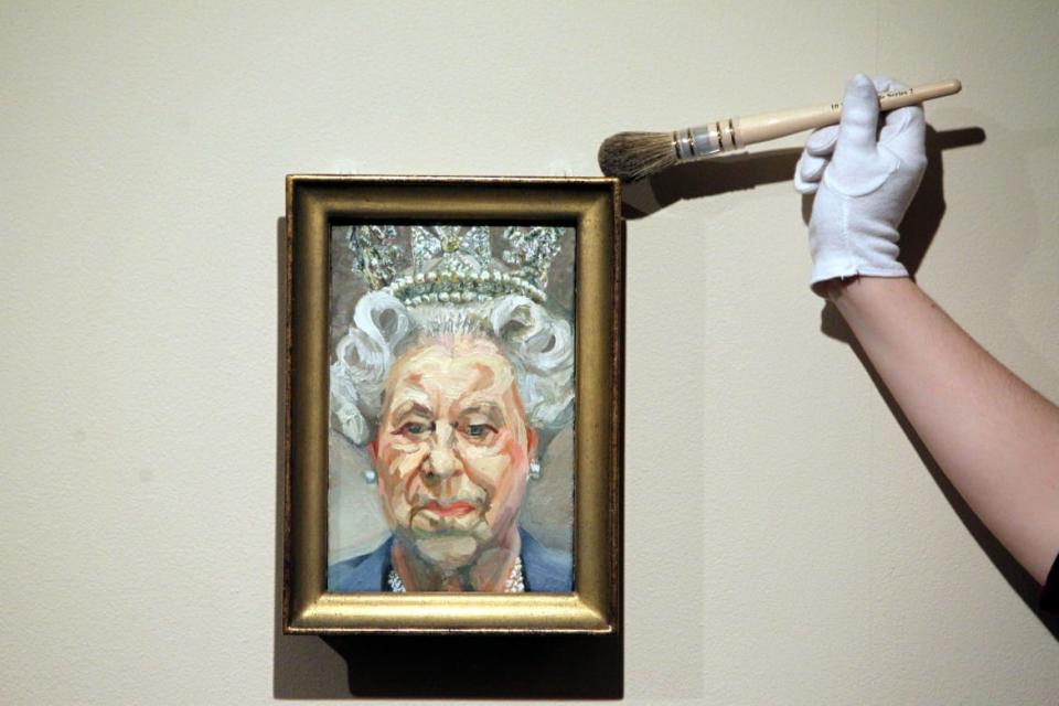 Curator Lauren Porter dusts a portrait by Lucian Freud of Queen Elizabeth II as part of the exhibition The Queen: Portraits of a Monach being shown at Windsor Castle.