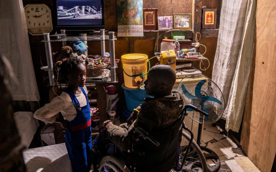 Olivier Bakweto, a polio survivor, talks to his daughter inside his home. He and his family are squatters in a complex with over 54 handicapped families - Diana Zeyneb Alhindawi/United Nations Foundation