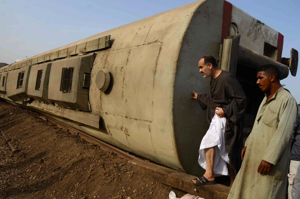 People gather at the site where a passenger train derailed injuring at least 100 people, near Banha, Qalyubia province, Egypt, Sunday, April 18, 2021. At least eight train wagons ran off the railway, the provincial governor's office said in a statement. (AP Photo/Tarek Wagih)