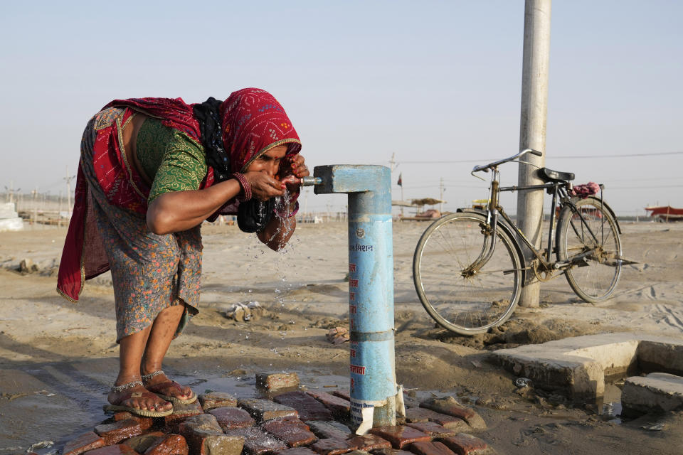 A woman drinks water from a public tap near the River Ganges on a hot summer day in Prayagraj, India, Thursday, May 2, 2024. (AP Photo/Rajesh Kumar Singh)