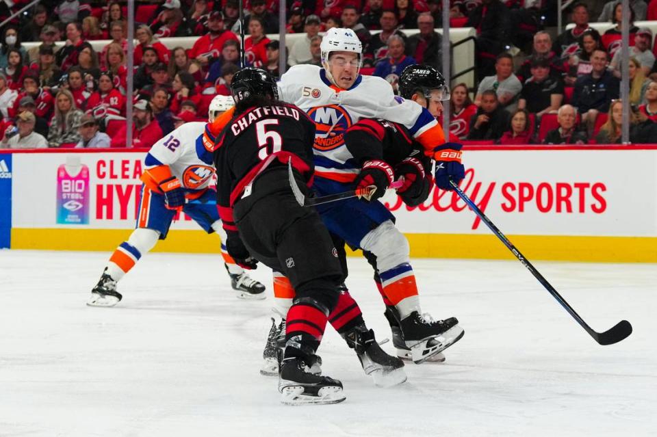 New York Islanders center Jean-Gabriel Pageau (44) is checked by Carolina Hurricanes defenseman Jalen Chatfield (5) and right wing Jesse Puljujarvi (13) during the second period at PNC Arena.