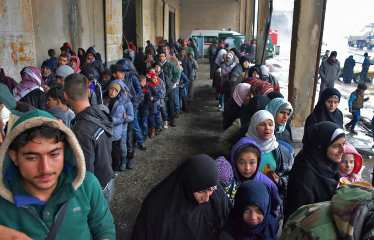 Syrians who fled from rebel-held areas in east Aleppo receive food aid on December 1, 2016 at a warehouse in Duweirineh, a small village on the eastern outskirts of the embattled city