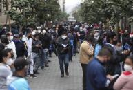 People wait in line for some businesses to reopen in downtown Lima, Peru, Wednesday, July 1, 2020. Major cities including the capital, will begin allowing for public transportation and certain businesses to reopen, but will still restrict the movement of the elderly and young children. (AP Photo/Martin Mejia)