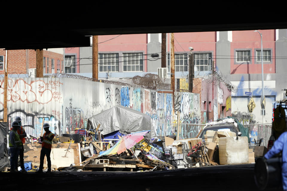 Workers stage under a fire-damaged freeway overpass along interstate 10 Monday, Nov. 13, 2023, in Los Angeles. Los Angeles drivers are being tested in their first commute since a weekend fire that closed a major elevated interstate near downtown. (AP Photo/Ryan Sun)