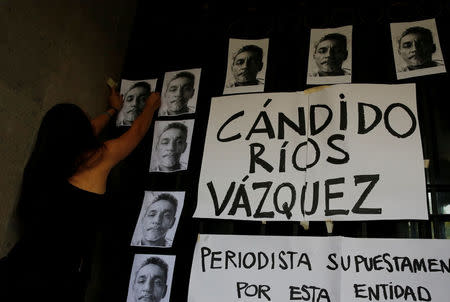 A journalist places pictures of reporter Candido Rios, who was killed in Veracruz, during a demonstration against his killing, at the Interior Ministry building in Mexico City, Mexico August 24, 2017. REUTERS/Henry Romero