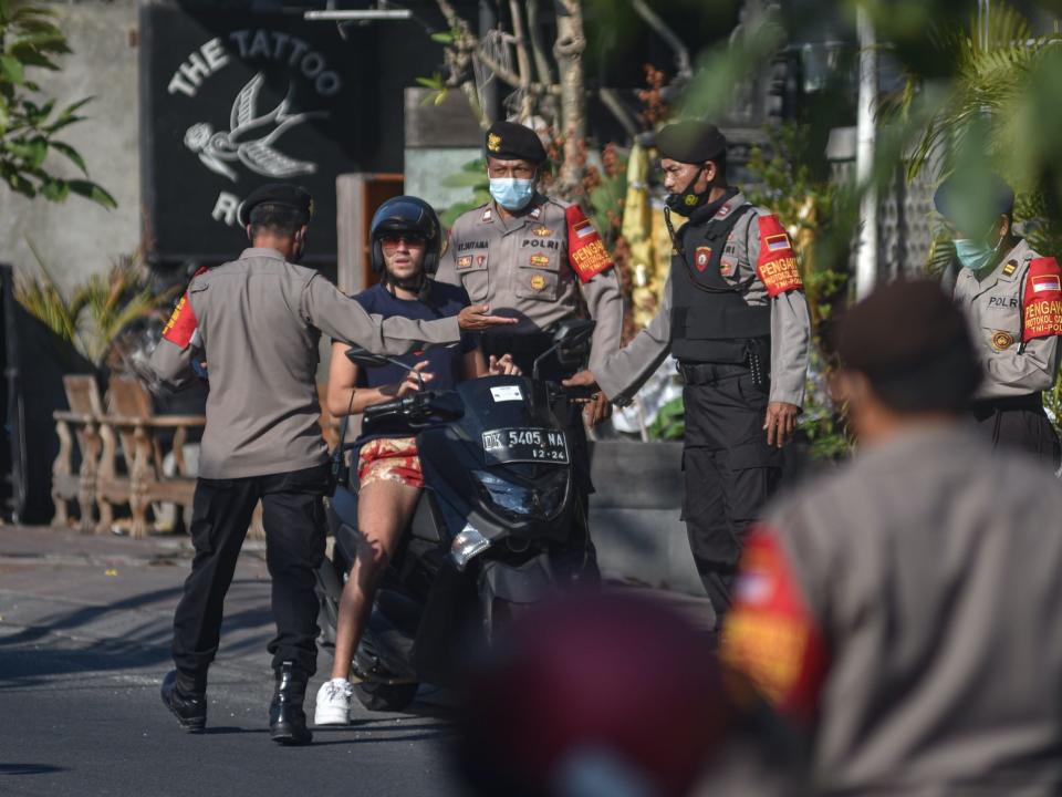 police in bali stop a man on a motorcycle not wearing a face mask