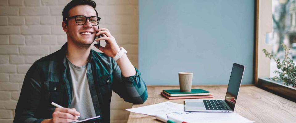 Cheerful male freelancer making telephone call