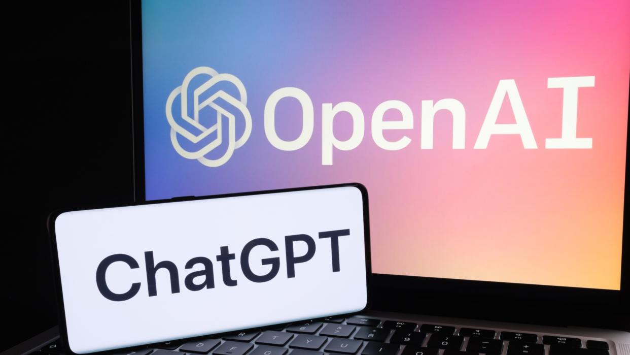  ChatGPT logo on phone sitting on laptop with OpenAI logo. 